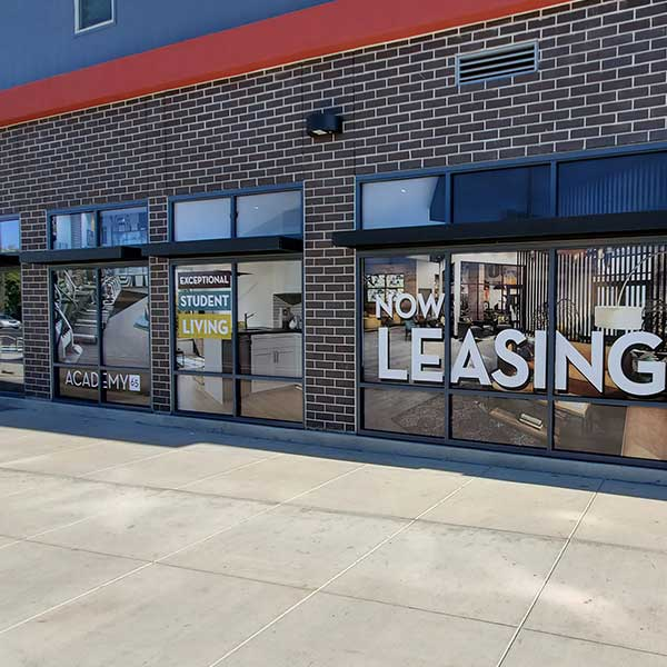 Large-format printed NOW LEASING window graphics installed at the Academy 65 leasing office in Sacramento