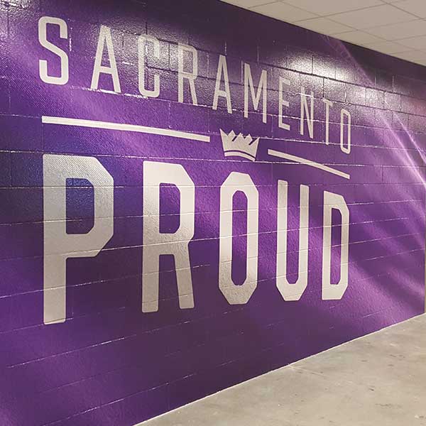 Sacramento Proud wall wrap applied across a painted block wall in an arena corridor